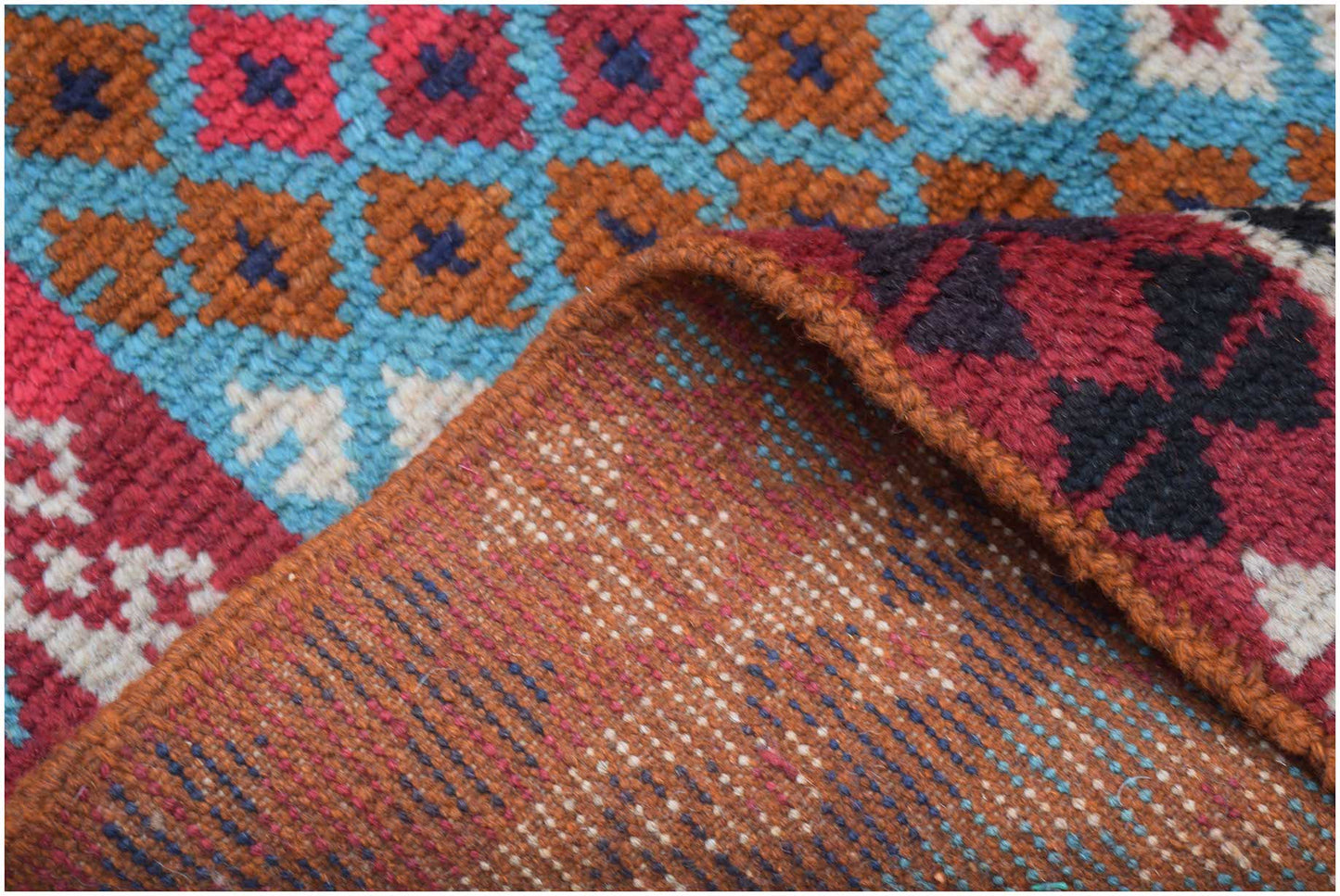 A handmade Afghan Pashm rug featuring a geometric pattern in red, blue, brown, and ivory wool.