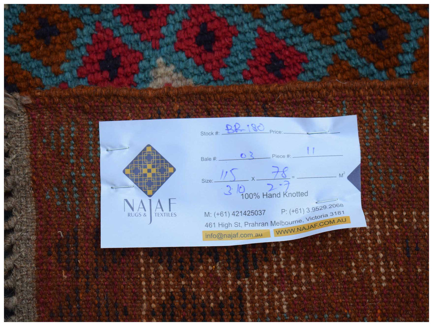 A handmade Afghan Pashm rug featuring a geometric pattern in shades of red, brown, and blue.