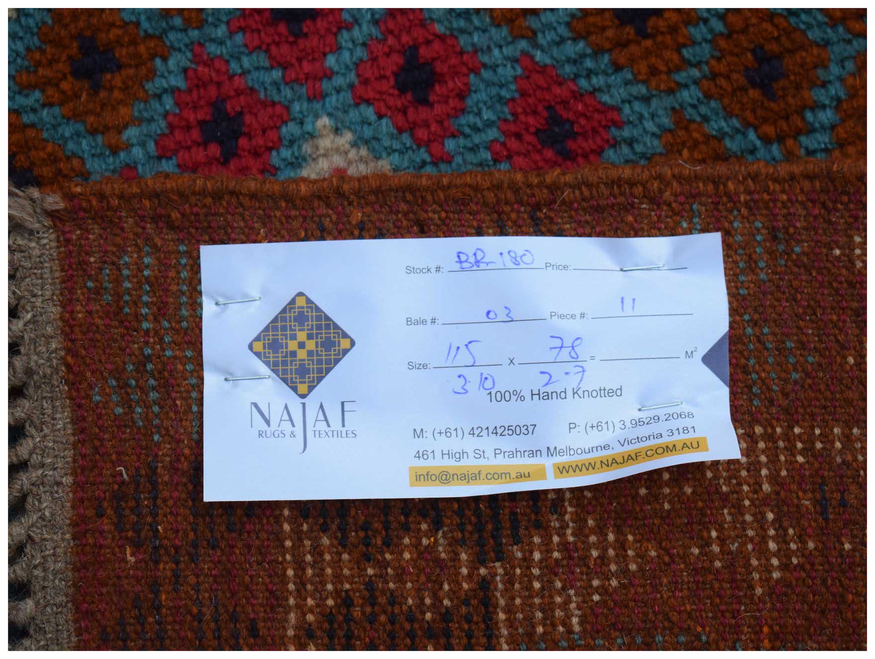A handmade Afghan Pashm rug featuring a geometric pattern in shades of red, brown, and blue.