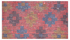 A close-up of a handmade Afghan Pashm rug featuring a geometric pattern in red, blue, and brown.