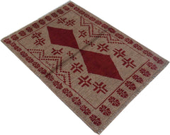 A handmade Afghan Pashm rug featuring a geometric diamond pattern in deep red on a tan background.