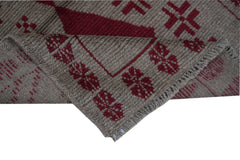 A handmade Afghan Pashm rug featuring a geometric tribal pattern in deep red on a brown wool base.