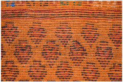 A handmade Afghan Pashm rug featuring a geometric pattern in shades of orange, brown, and red.