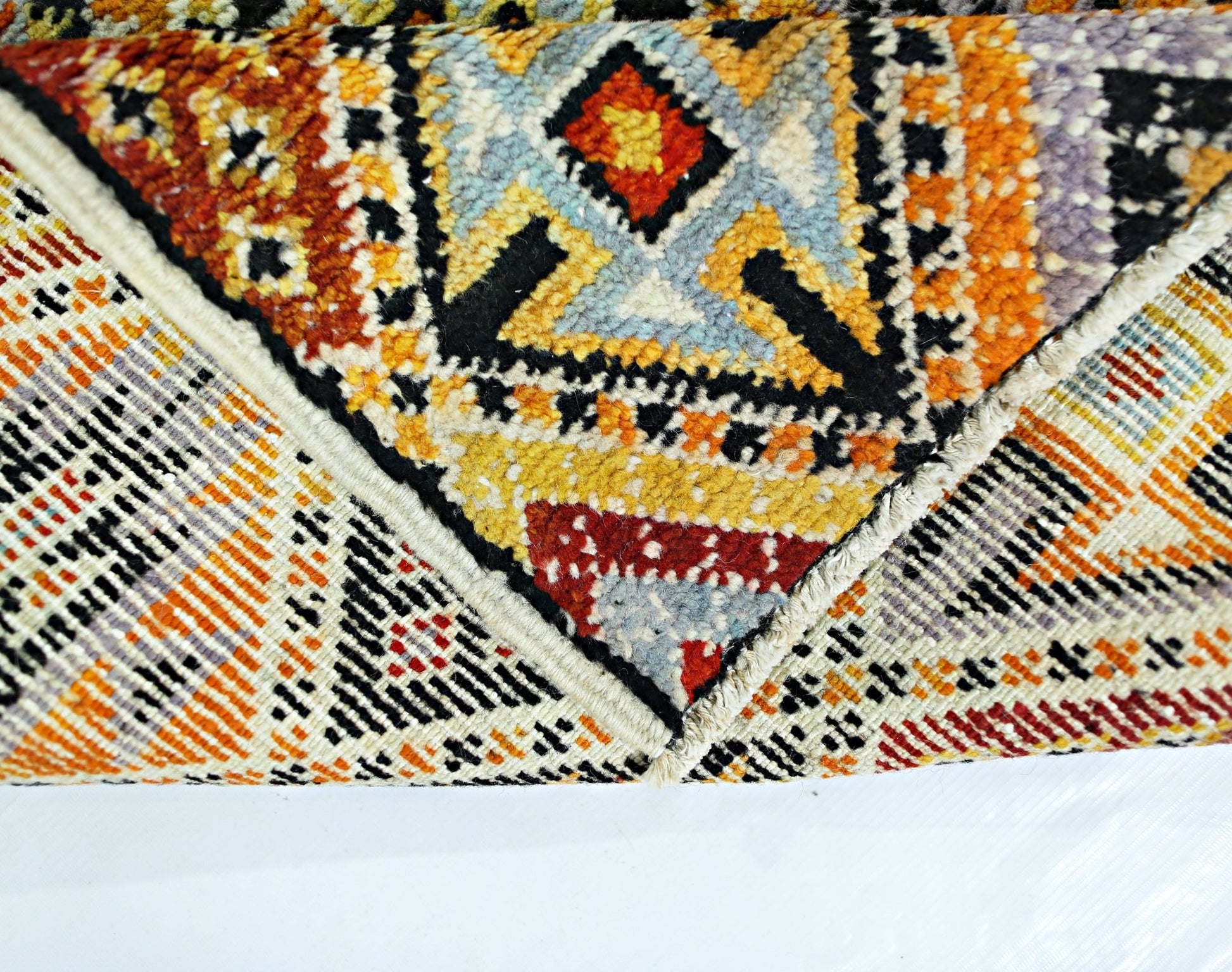 A hand-knotted Afghan wool rug featuring bold geometric patterns in vibrant orange and yellow tones.
