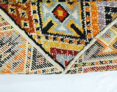 A hand-knotted Afghan wool rug featuring bold geometric patterns in vibrant orange and yellow tones.
