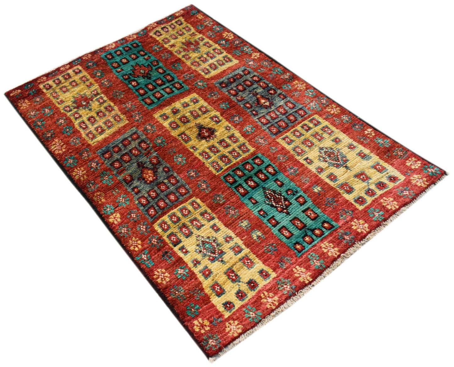 An Afghan Pashm rug featuring a red background with geometric blocks in yellow and teal.