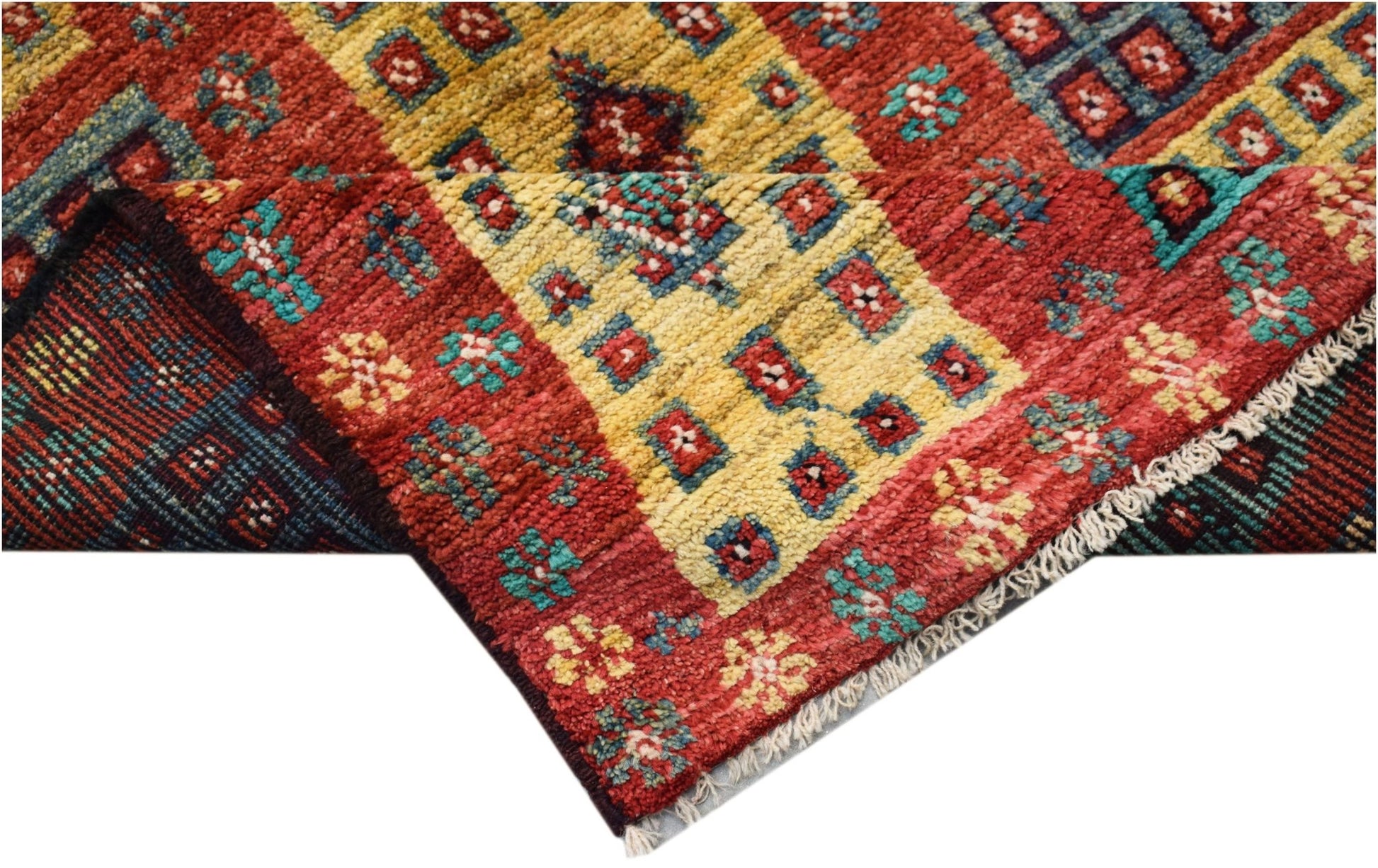 A hand-knotted Afghan wool rug featuring a geometric pattern in red, yellow, and teal.