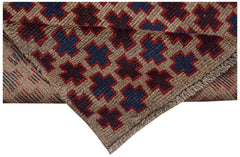 A handmade Afghan Pashm rug featuring a repeating cross pattern in dark red, blue, and brown wool.