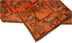 An orange hand-knotted Afghan wool rug featuring a repeating pattern of camels and trees.