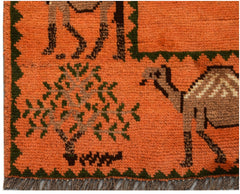 An orange Afghan wool rug featuring a hand-knotted pattern of a tree and a camel.