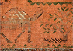 A close-up of an orange Afghan wool rug featuring dark geometric patterns and a fringed edge.
