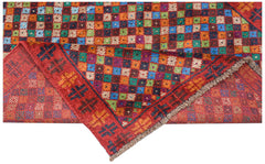 A handmade Afghan Pashm rug featuring a vibrant, multi-colored checkered pattern on a red base.