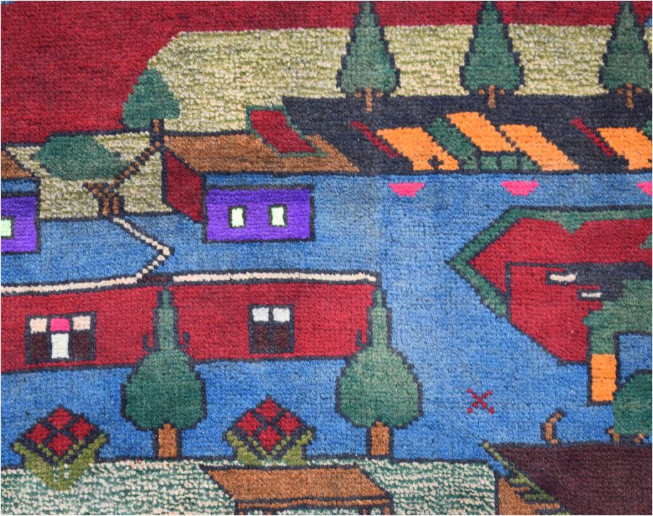 Handmade Afghan wool rug featuring a colorful, stylized landscape with houses and trees.