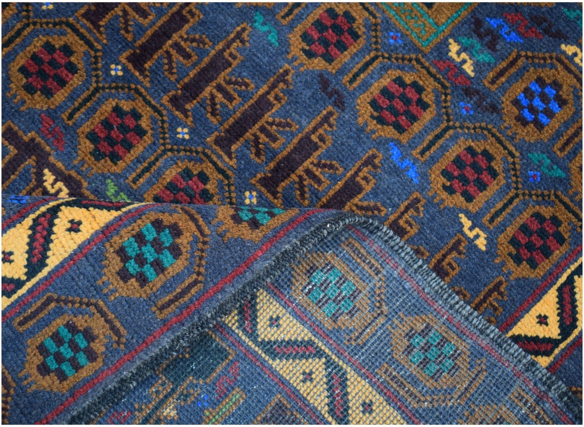 A handmade Afghan wool rug featuring a geometric pattern in blue, gold, red, and green.