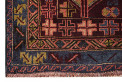 A handmade Afghan Pashm rug featuring geometric patterns in deep red, blue, and brown wool.