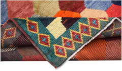A hand-knotted Afghan wool rug featuring a colorful geometric pattern and a folded corner.
