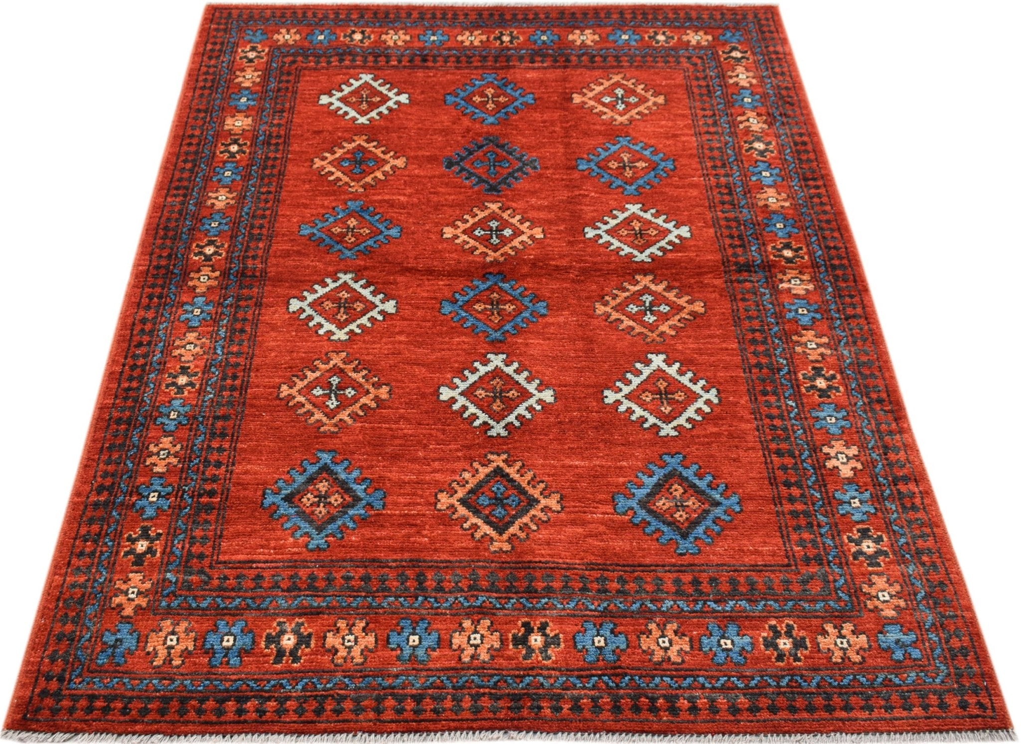 A handwoven Afghan Pashm rug featuring a red field with repeating geometric motifs.