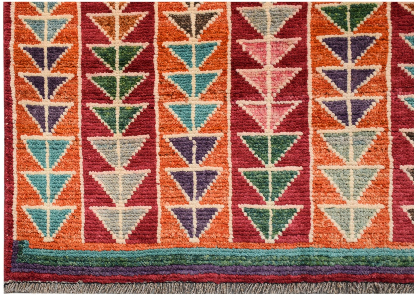 Hand-knotted Afghan wool rug featuring vertical stripes of colorful geometric triangle patterns.