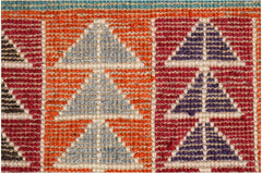 A close-up of a hand-knotted Afghan wool rug featuring geometric triangle patterns in vibrant colors.