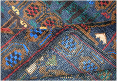 A close-up of a handmade Afghan wool rug featuring geometric patterns in blue, red, and brown.