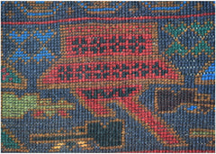 A close-up of a handmade Afghan wool rug featuring geometric patterns in red, blue, and green.