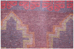 A close-up of a handmade Afghan Pashm rug featuring geometric patterns in red, brown, and blue.