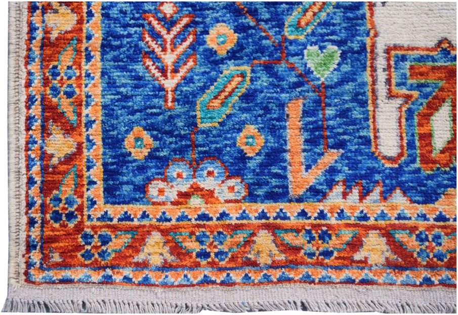A handmade Afghan wool rug featuring a vibrant blue field with colorful tribal floral motifs.