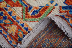 A folded Afghan Pashm rug featuring a vibrant tribal pattern in orange, blue, and green wool.