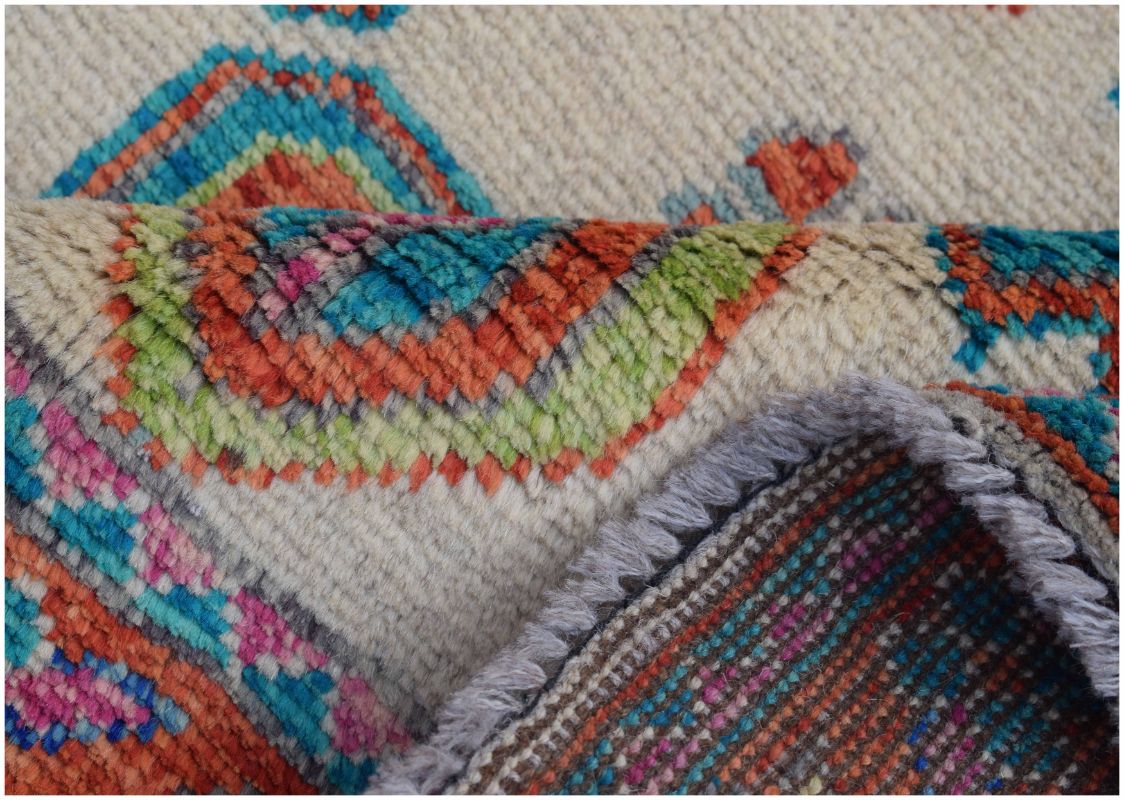A close-up of a handmade Afghan wool rug featuring colorful tribal patterns on a cream background.