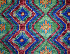 Handmade Afghan wool rug featuring a vibrant geometric diamond pattern in blue, green, and orange.