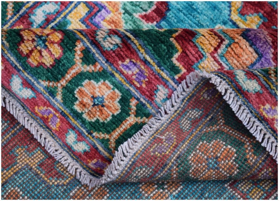 A handmade Afghan Pashm wool rug featuring a vibrant, colorful tribal pattern with floral motifs.