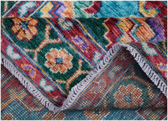 A handmade Afghan Pashm wool rug featuring a vibrant, colorful tribal pattern with floral motifs.