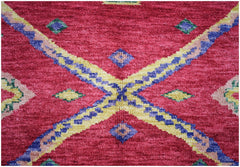 A handknotted Afghan wool rug featuring a vibrant red field with geometric blue and yellow patterns.