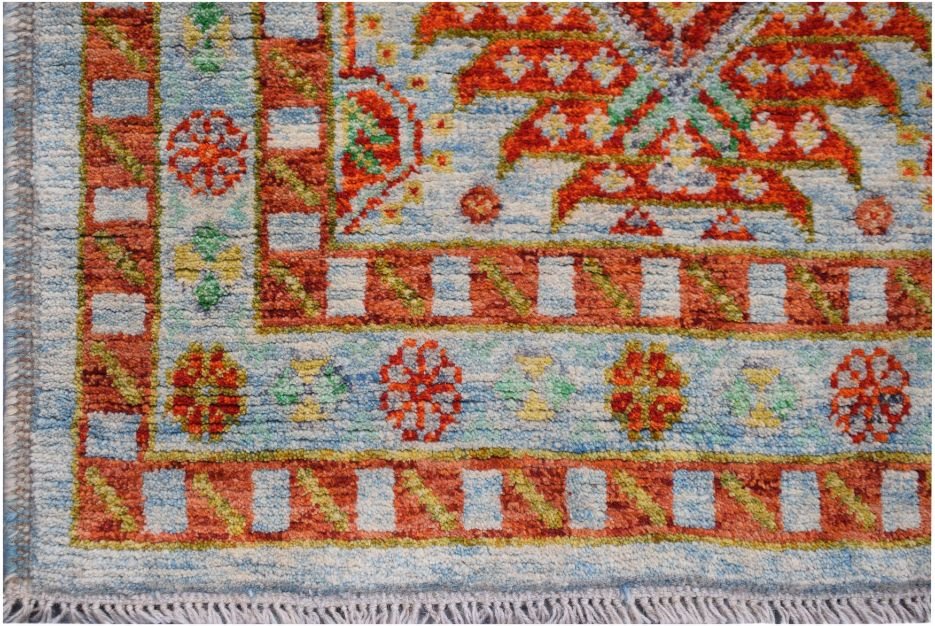 A handmade Afghan Pashm rug featuring a vibrant geometric pattern in red, blue, and green.