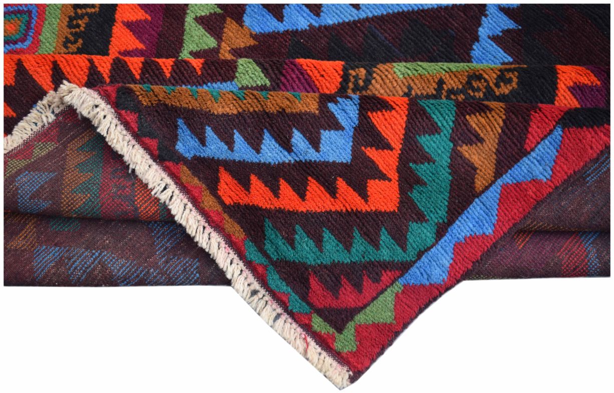 A handmade Afghan wool rug featuring a vibrant geometric tribal pattern in a folded display.