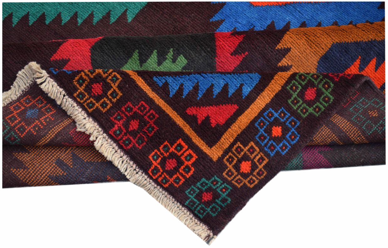 A handmade Afghan wool rug featuring colorful geometric patterns and a fringed edge.