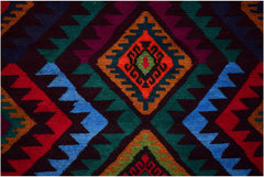 Handmade Afghan wool rug featuring a vibrant geometric diamond pattern in red, blue, and green.