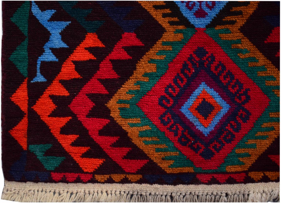 A handmade Afghan wool rug featuring a vibrant geometric diamond pattern in red, blue, and gold.