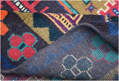 A handmade Afghan Pashm rug featuring a dark, geometric tribal pattern in red, blue, and brown.