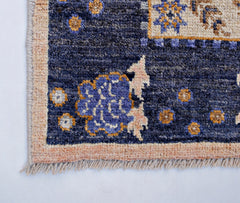 A handmade Afghan Pashm wool rug featuring a deep blue field with floral motifs and a beige border.