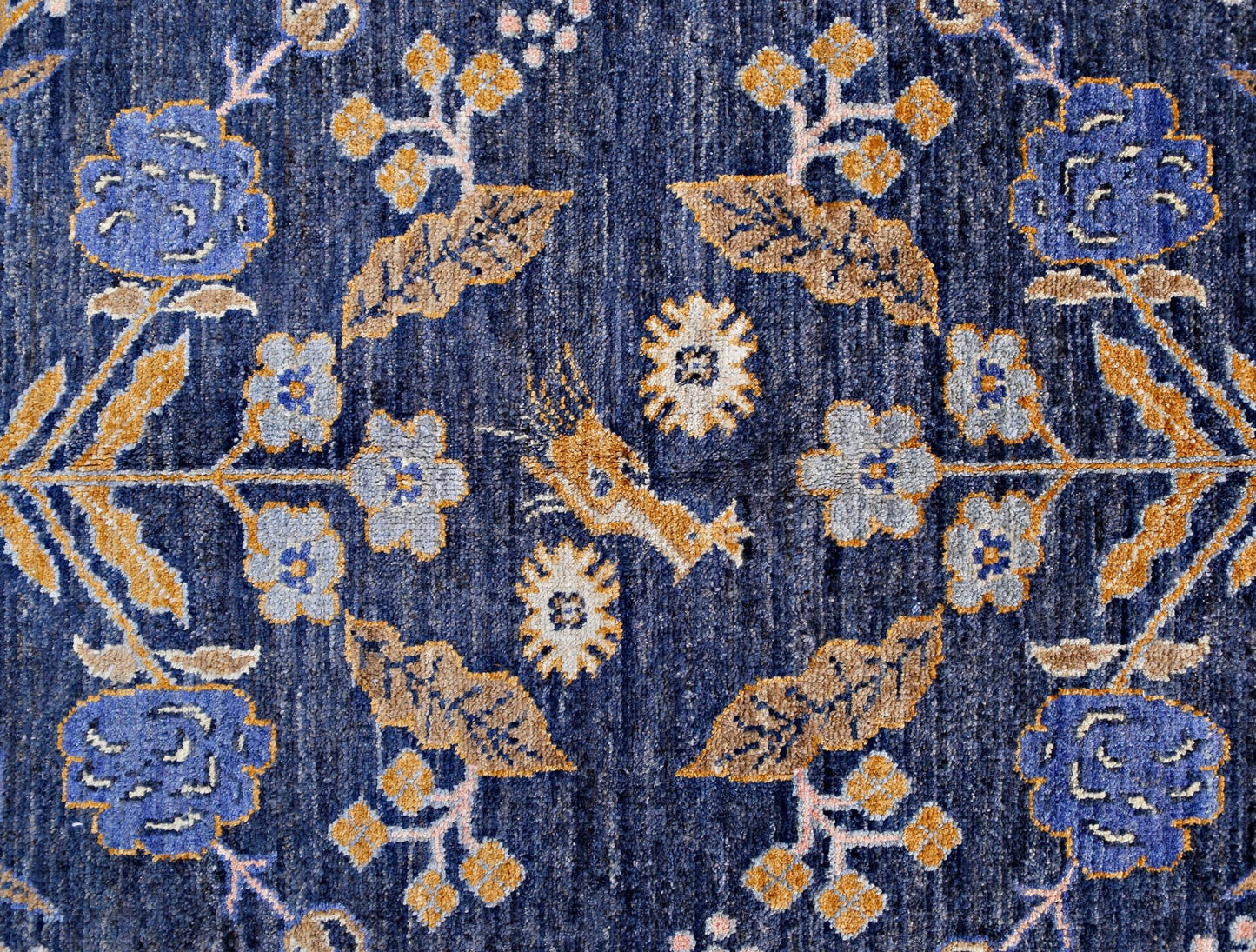 Handmade Afghan Pashm wool rug featuring a symmetrical floral pattern in blue, gold, and cream.