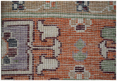 A close-up of a handmade Afghan wool rug featuring geometric tribal patterns in orange and purple.