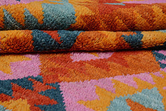 A handmade Afghan wool rug featuring a vibrant, plush pattern of orange, pink, and blue shapes.