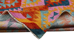 A handmade Afghan wool rug featuring a vibrant geometric pattern in orange, pink, and blue.