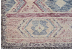 A handmade Afghan wool rug featuring a geometric tribal pattern in shades of blue, pink, and cream.