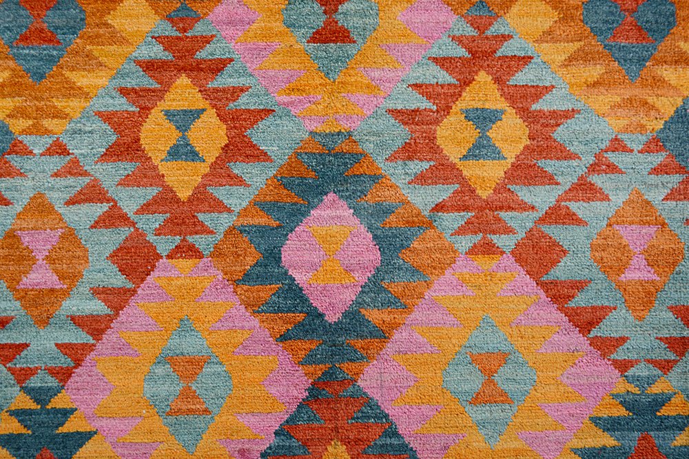 Handmade Afghan wool rug featuring a geometric diamond pattern in orange, pink, and blue.