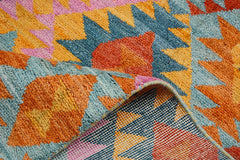 A handmade Afghan wool rug featuring a vibrant geometric pattern in blue, orange, pink, and yellow.