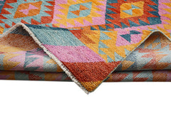 A handmade Afghan wool rug featuring a vibrant geometric pattern in pink, orange, and blue.
