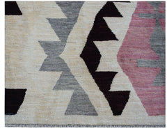 A handmade Afghan wool rug featuring a geometric tribal pattern in cream, grey, black, and pink.