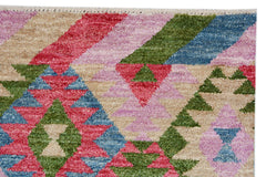 Handmade Afghan wool rug featuring a vibrant geometric pattern in pink, green, blue, and tan.